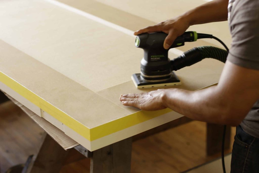 Worker sanding block of wood